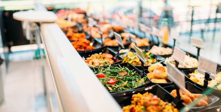 A deli counter full of delicious looking food including a green bean salad, croquettes and some fried foods.