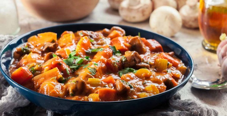 A delicious vegan irish stew is served in a blue bowl.