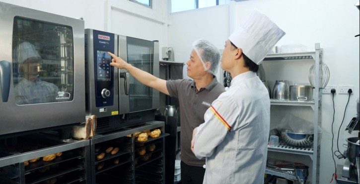 Chef receiving guidance on the RATIONAL iCombi Pro combi oven touchscreen.