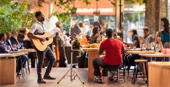 Musician playing guitar in a lively outdoor space.