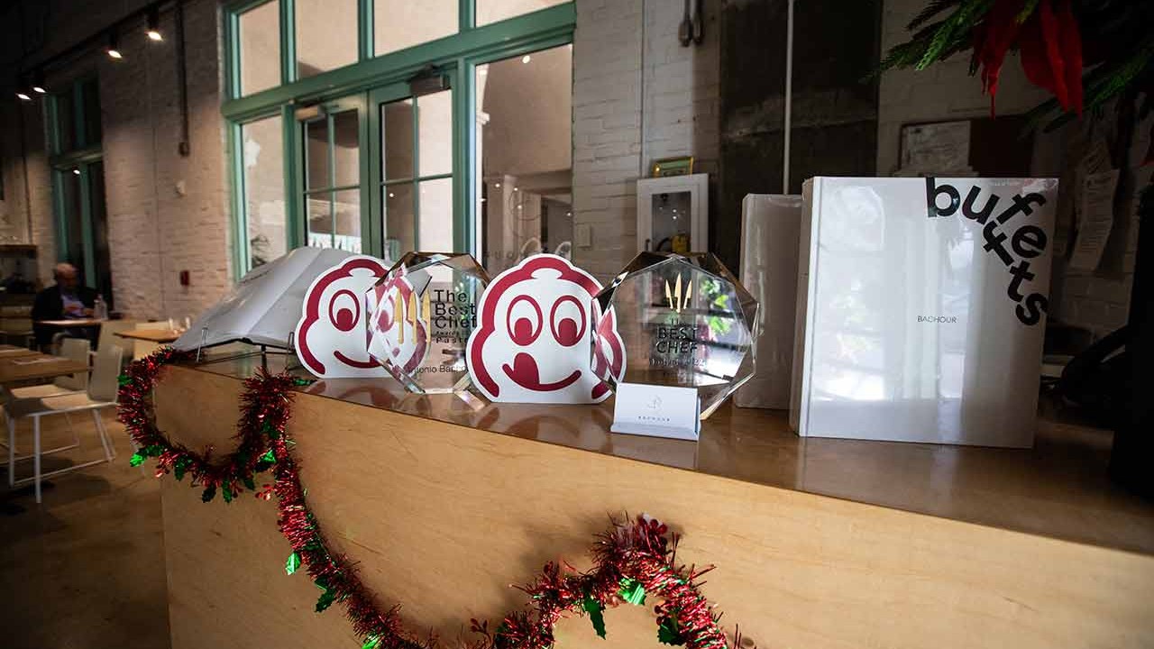 A restaurant counter displaying awards, menus, and festive decorations at Bachour.
