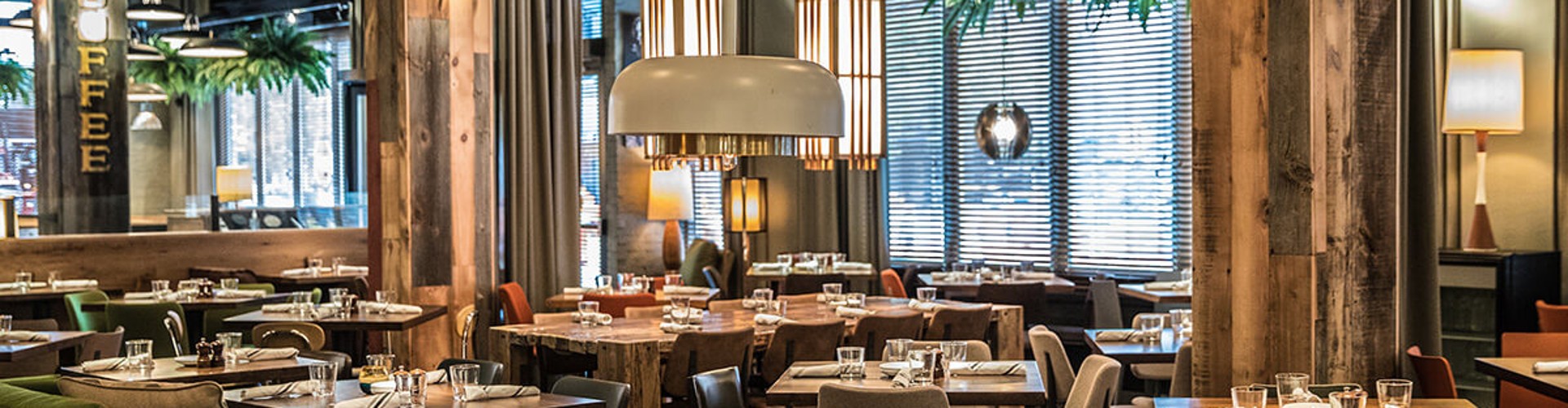 Interior view of a modern restaurant featuring wooden tables, comfortable seating, and stylish lighting.