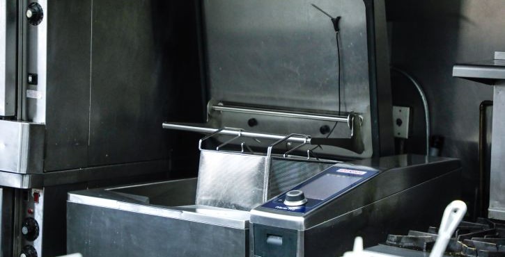 Commercial deep fryer with metal basket in a professional kitchen.