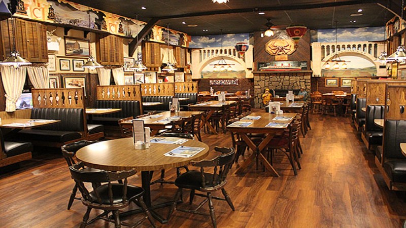 The interior of Cooper‘s Seafood House, showcasing wooden tables and black leather booths, decorated with nautical-themed artwork and photos.
