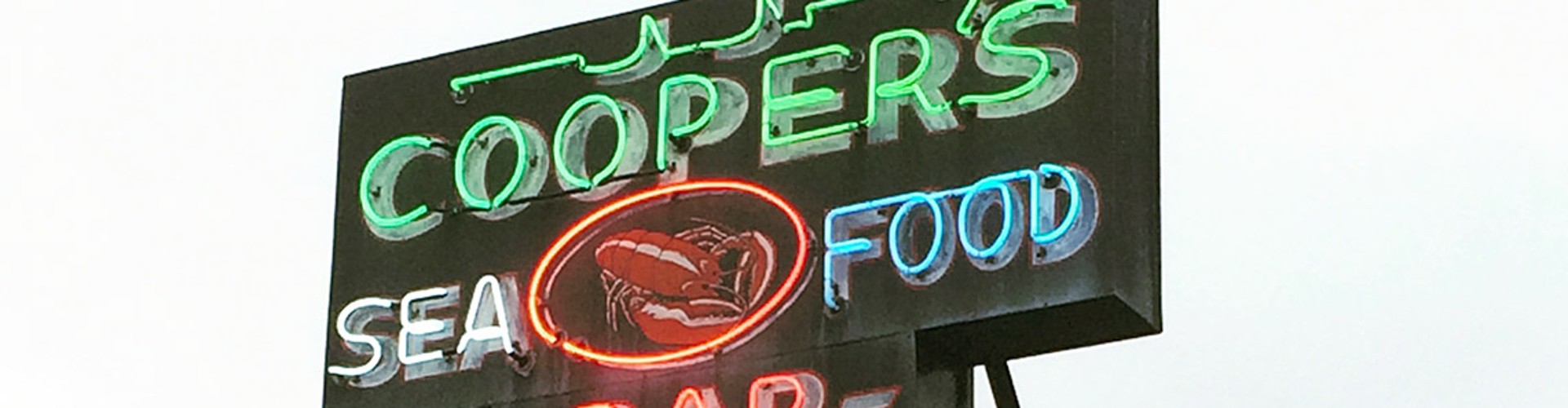 The illuminated sign of Cooper‘s Seafood House, featuring colorful neon lights with the text "Cooper‘s Seafood Bar."