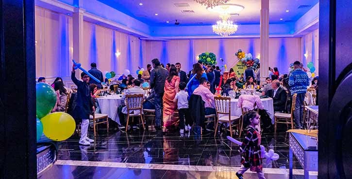 A lively restaurant party scene with guests dining, colorful balloons, and decorations in a vibrant setting.