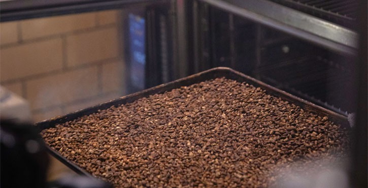 A close-up of a tray filled with freshly roasted coffee beans.