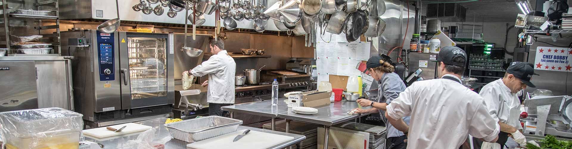 A busy commercial kitchen with chefs working, preparing food, and using a Rational combi oven.