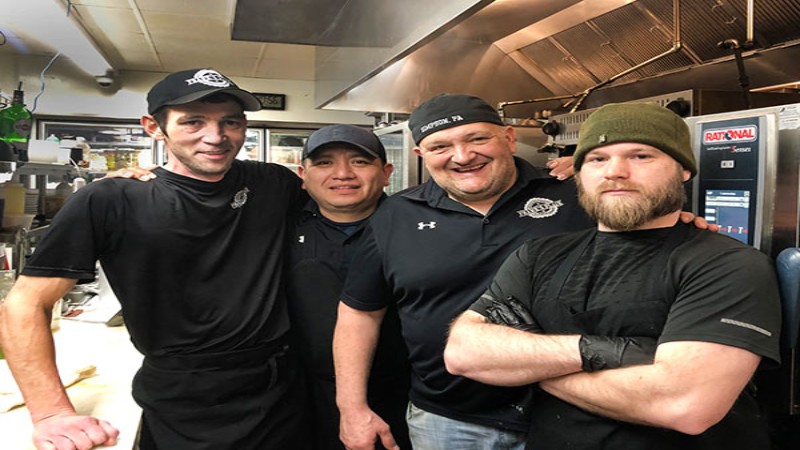 Group of four chefs smiling in the kitchen of Frank‘s Place restaurant.