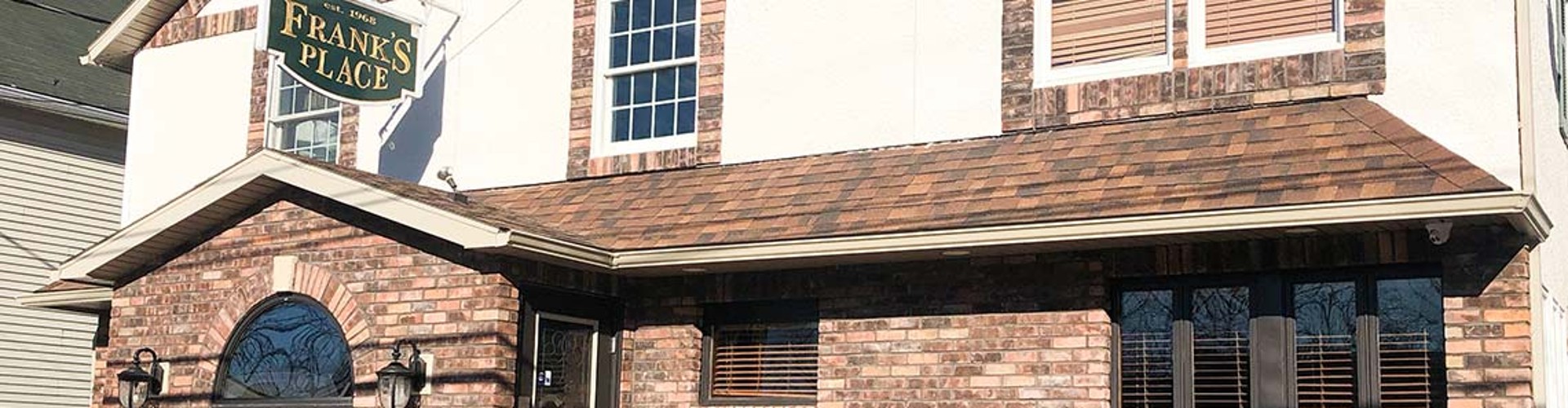 Close-up view of the entrance to Frank‘s Place restaurant, featuring brick walls and a sign.