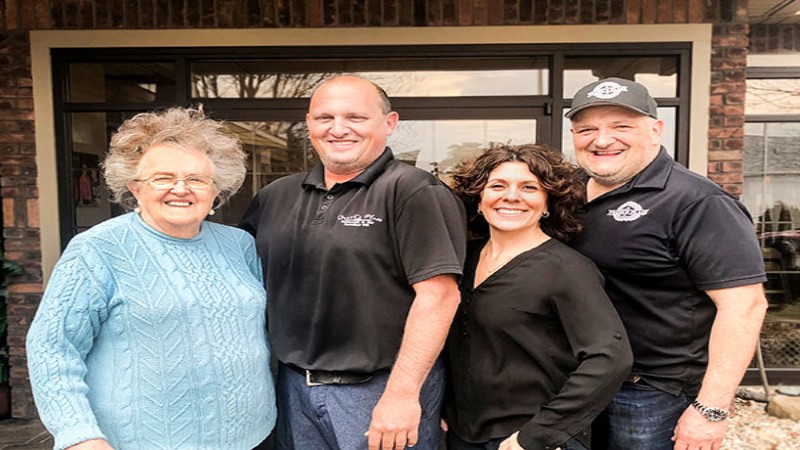 Group of four people posing together outside Frank‘s Place restaurant, smiling for the camera.