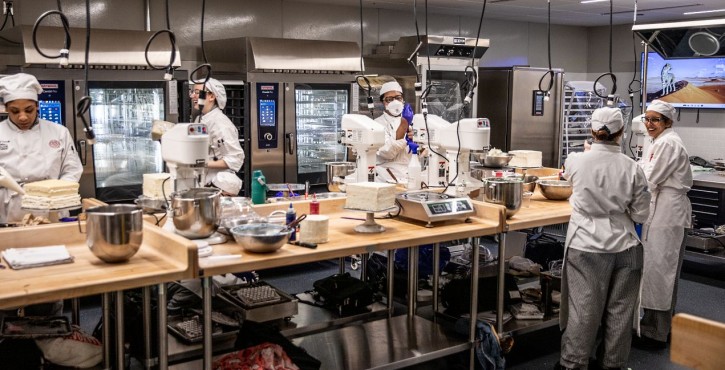 Culinary students preparing cakes in a training kitchen with RATIONAL iCombi Pro combi ovens.