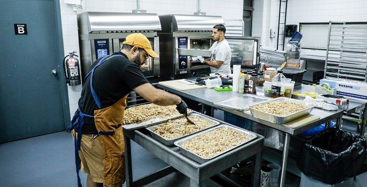 Chef portioning food trays in a commercial kitchen with RATIONAL iCombi Pro combi ovens in use.