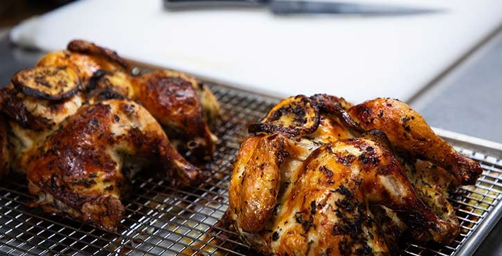 Two perfectly roasted chickens resting on a wire rack, ready for serving.