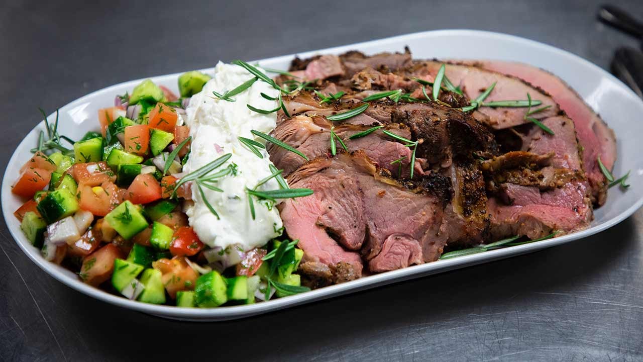 A plated dish featuring slices of roasted meat alongside a fresh salad and creamy dressing.