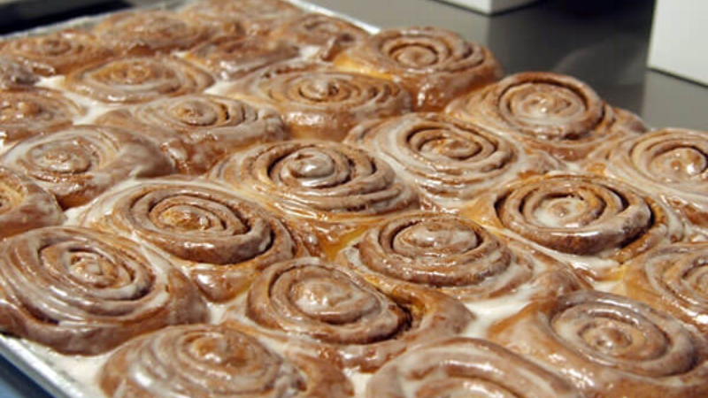 A tray of freshly baked cinnamon rolls with icing.