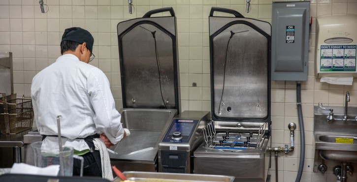 Chef working at a RATIONAL iVario Pro with open pans in a commercial kitchen.