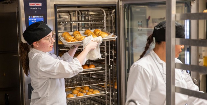 Chef removes trays of fresh rolls from a RATIONAL iCombi Pro combi oven.