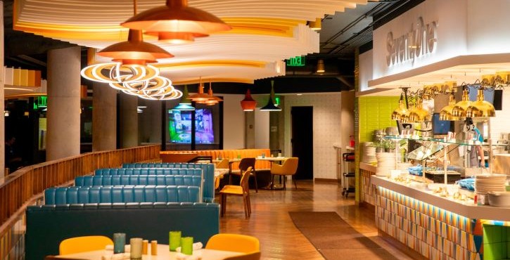 Modern dining area with booth seating and a self-serve station under curved ceiling lights.