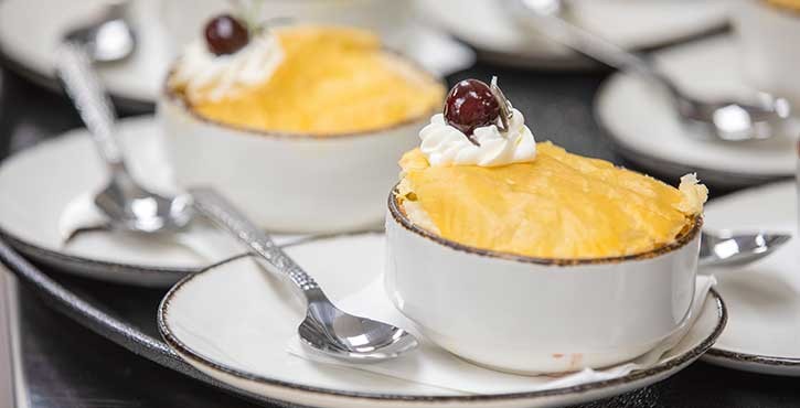 Plates of pineapple upside-down cake served with whipped cream and a cherry on top, displayed on a restaurant table.