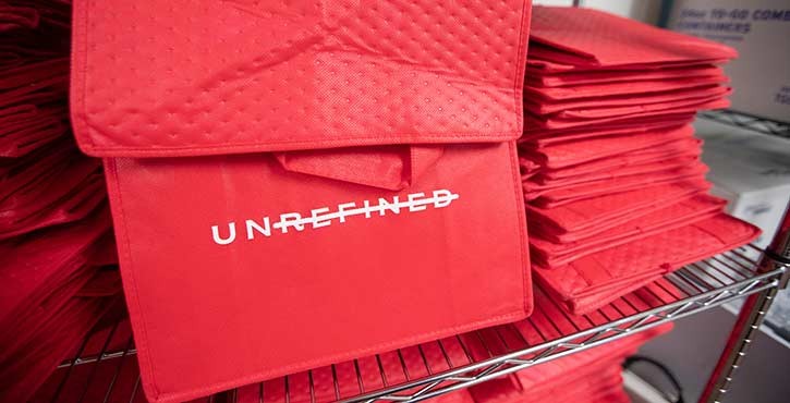 A stack of red bags with the word 'UNREFINED' printed on them, displayed in a kitchen setting.