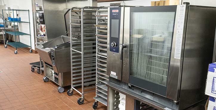 A professional kitchen equipped with a Rational oven, cooking racks, and stainless steel equipment.
