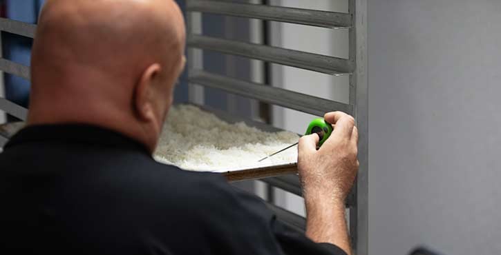 A chef measuring the temperature of a tray of rice in a professional kitchen setting.