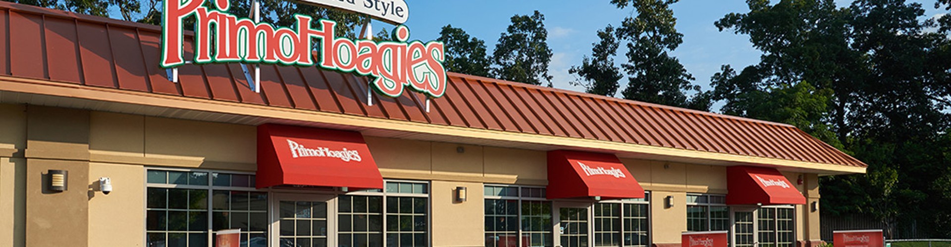 Exterior view of a Primo Hoagies restaurant building on a sunny day.