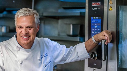 Chef in a professional kitchen standing next to a Rational iCombi Pro combi-steamer.