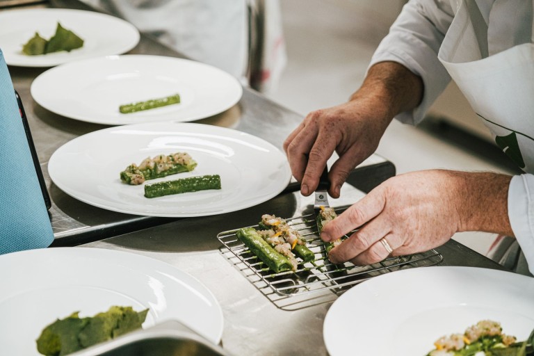 Chef dressant des rouleaux de courgette farcis aux légumes dans une cuisine gastronomique.