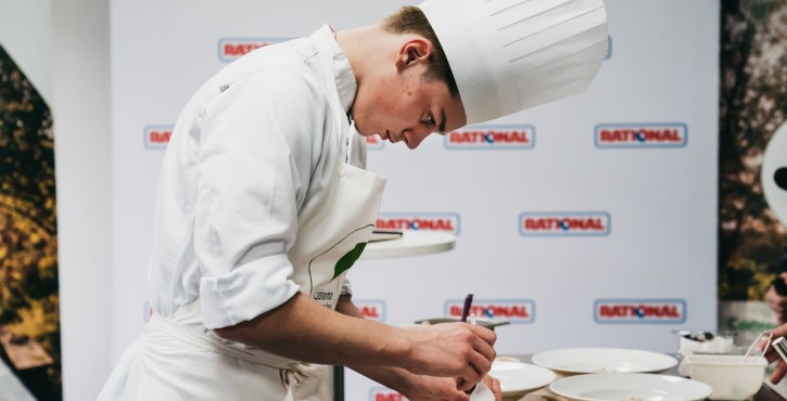 Jeune chef concentré dresse un plat avec précision lors du concours culinaire RATIONAL.