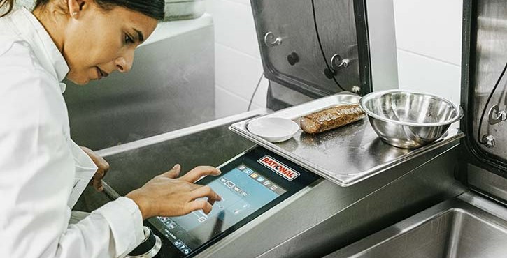 Cheffe utilisant le système de cuisson multifonction RATIONAL iVario Pro avec écran tactile en cuisine professionnelle.