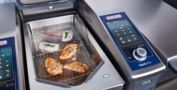 The iVario Pro advanced bratt pan from RATIONAL is on the Sous-vide setting with marinated chicken, fish and duck gently cooking in the pan.
