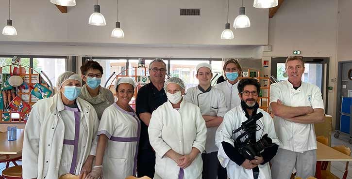 Équipe de cuisine et chefs posant ensemble dans une salle à manger lumineuse.