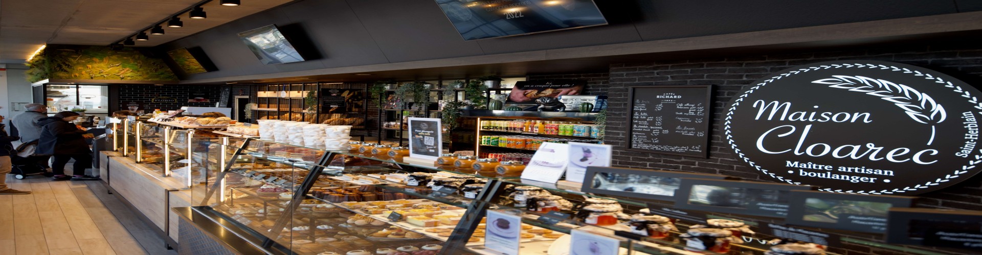 Comptoir de boulangerie chez Maison Cloarec avec viennoiseries, pains et clients en attente.