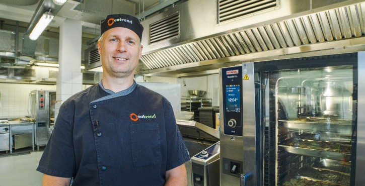Chef standing beside a RATIONAL iCombi Pro combi oven in a professional kitchen.