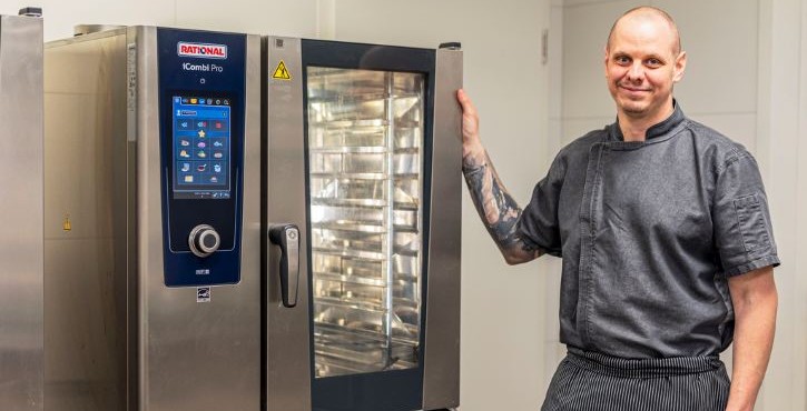 Chef standing beside a RATIONAL iCombi Pro combi oven in a professional kitchen.