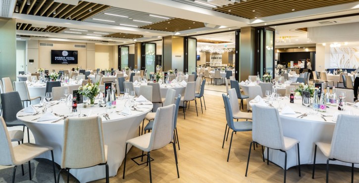 Modern hotel conference room with round banquet tables and elegant table settings.