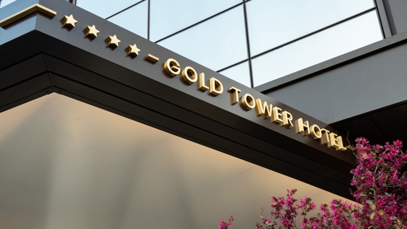 Vista esterna dell’ingresso del Gold Tower Hotel con insegna a quattro stelle e architettura moderna.