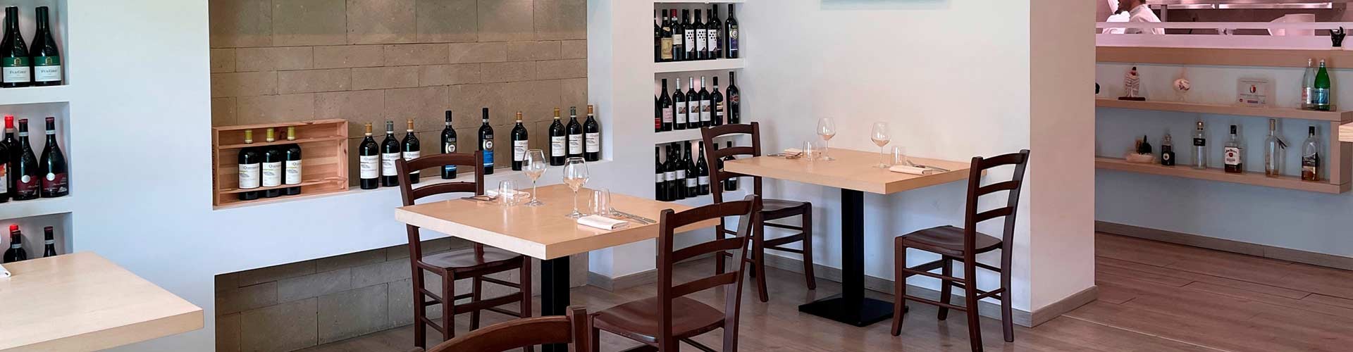 Sala del ristorante Bacalajuo con esposizione di vini e tavoli elegantemente apparecchiati.
