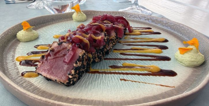 Tonno scottato in crosta di sesamo con cipolla rossa caramellata e salsa decorativa.
