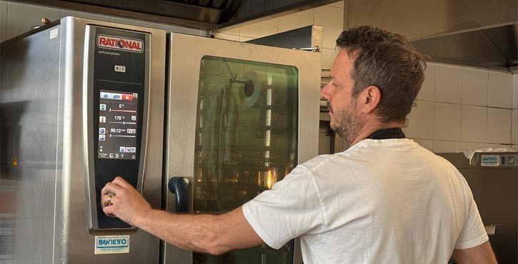 Chef utilizza il touchscreen del RATIONAL SelfCookingCenter forno professionale in una cucina professionale.