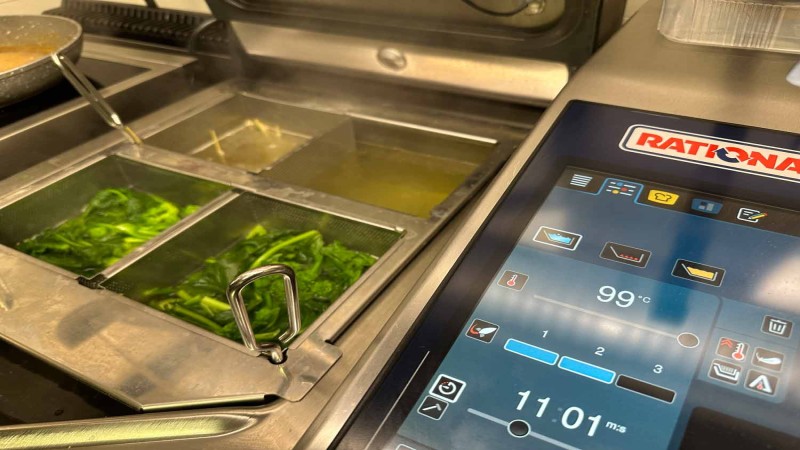 Verdure a foglia sbollentate nel RATIONAL iVario Pro con controllo touchscreen in cucina professionale.