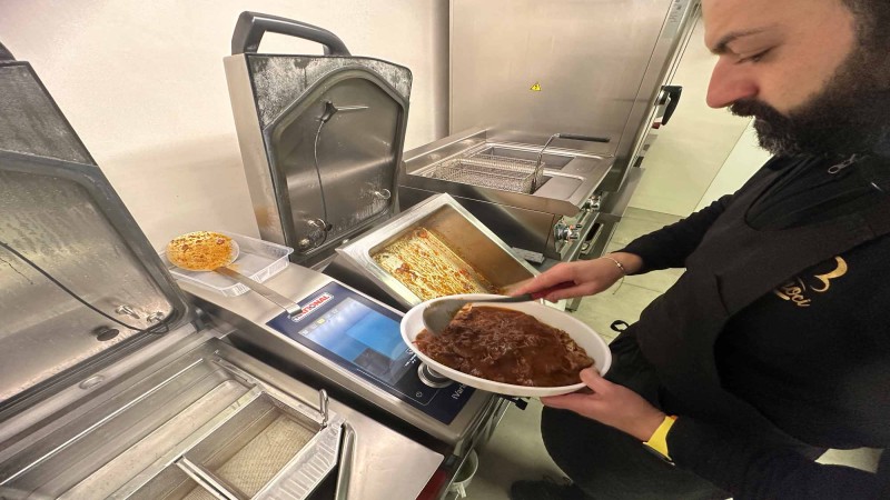 Chef impiatta carne a lenta cottura preparata con RATIONAL iVario Pro in cucina professionale.