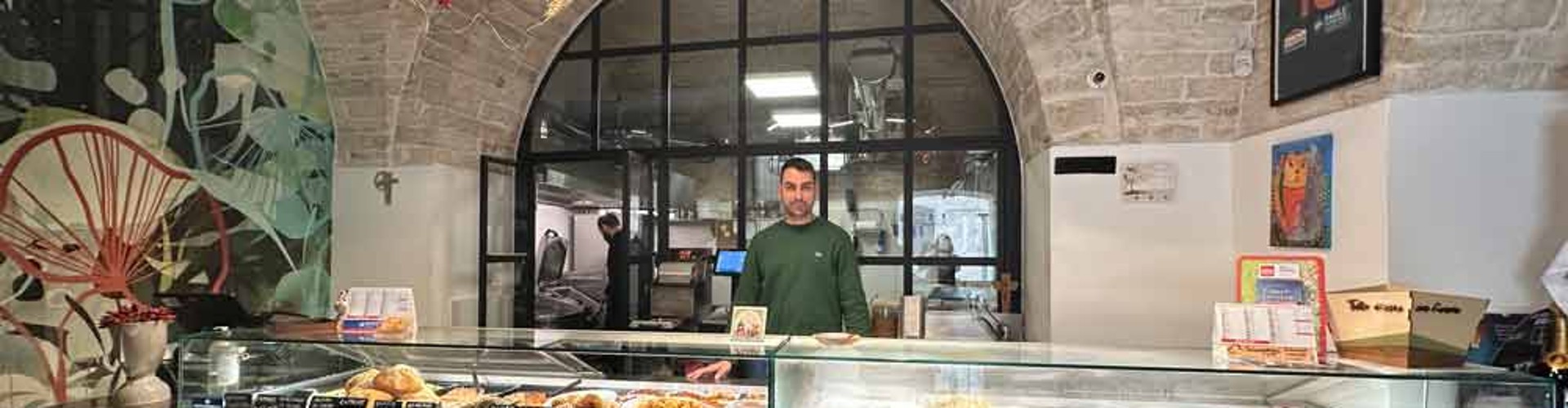 Banco gastronomia Deliziamoci con piatti pronti e addetto in un ambiente rustico con volte.
