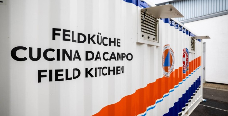 Contenitore cucina da campo mobile con scritte multilingue per uso d‘emergenza.