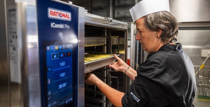 Chef placing tray of food into RATIONAL iCombi Pro combi oven.