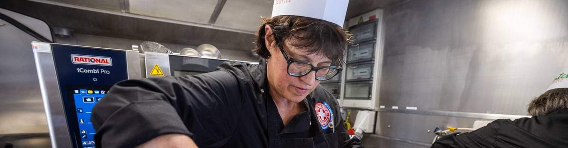 Cuoca prepara rotoli di pane accanto al RATIONAL iCombi Pro forno professionale.