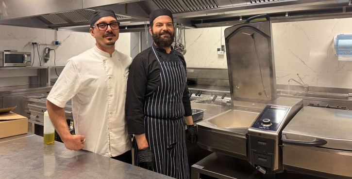 Due chef accanto a un RATIONAL iVario in una cucina professionale.