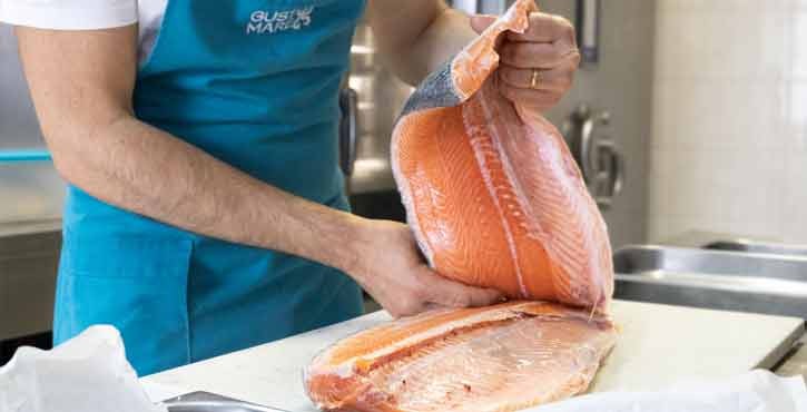 Chef prepara filetti di salmone fresco nella cucina di un ristorante di pesce.